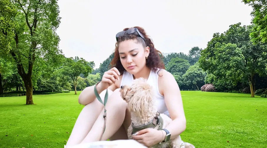 Rojan sitting on the grass, saying hello to a small dog.